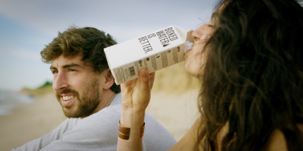 A woman drinking a Boxed Water carton