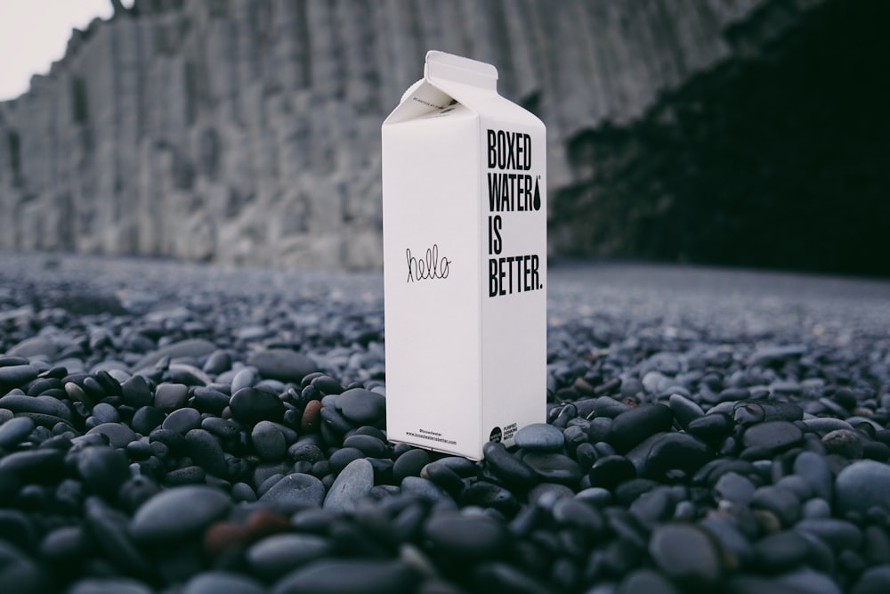 A carton of Boxed Water on a black beach