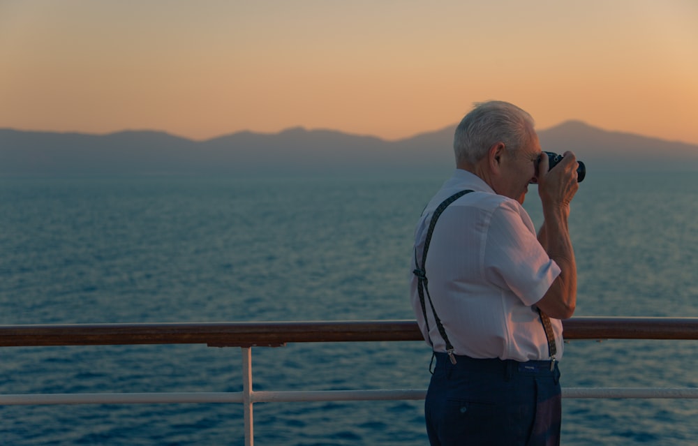 man holding DSLR while standing on deck