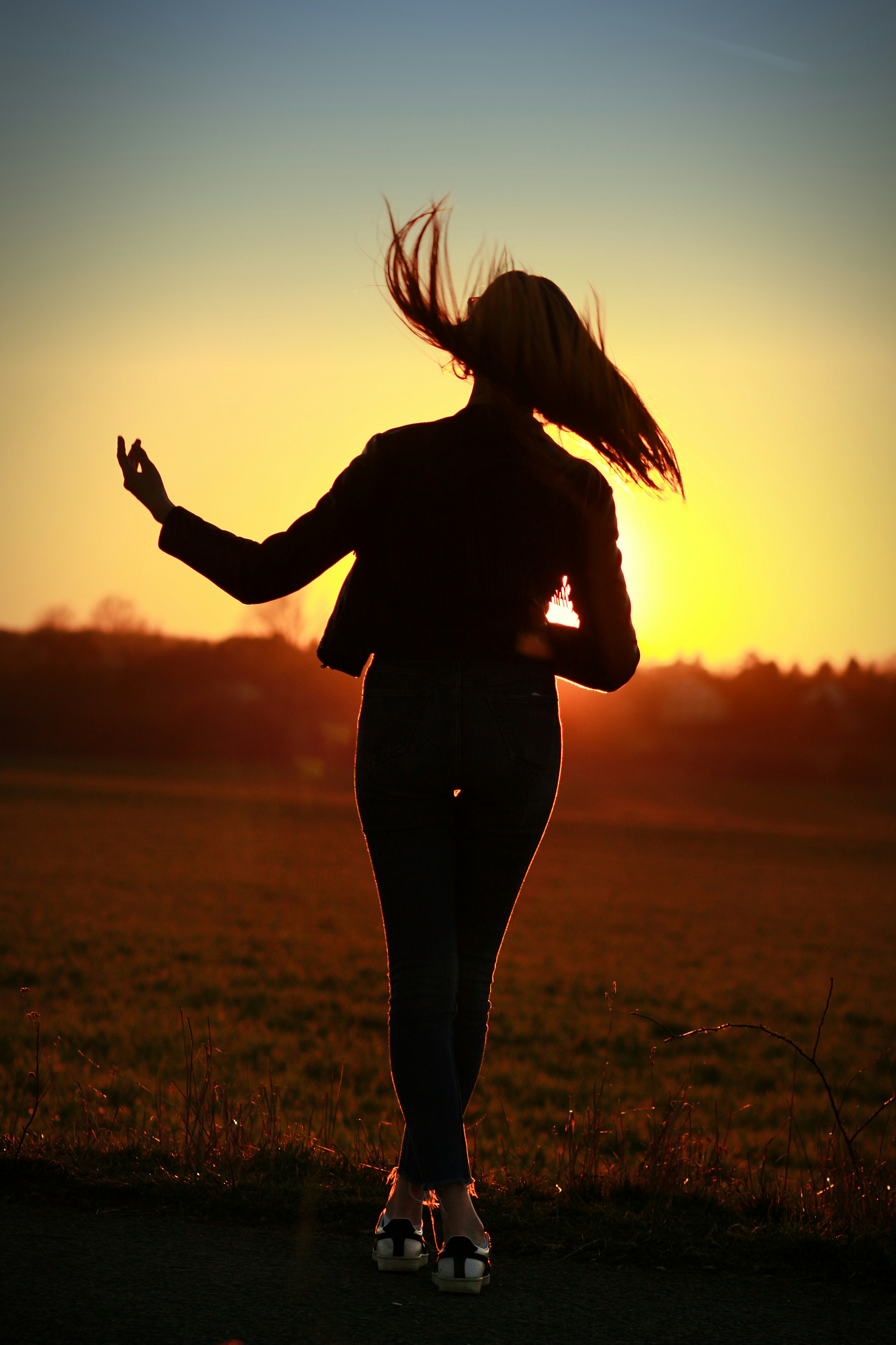 endless time, girl with flying hair in front of a sunset in the summer silouette