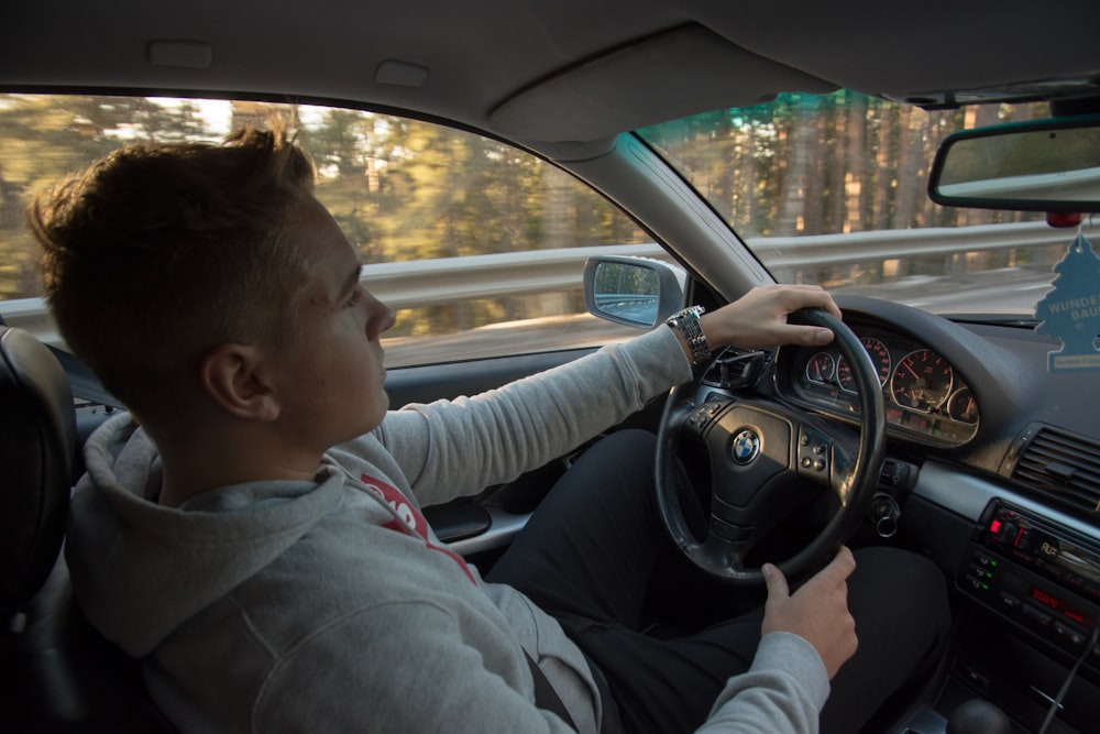 man wearing gray hoodie driving car