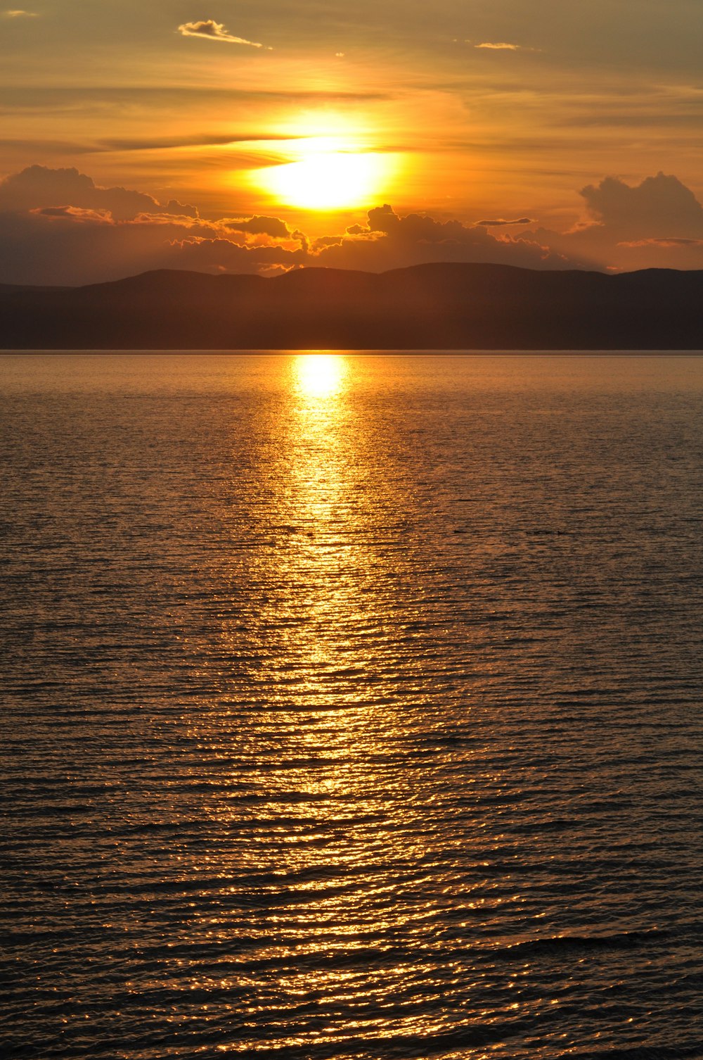 calm body of water overlooking mountain range during golden hour