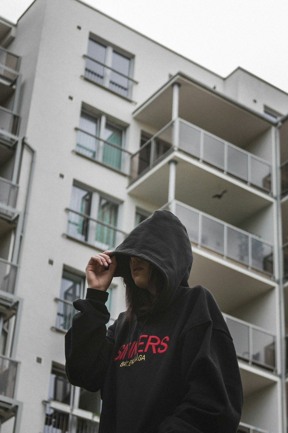 woman wearing pullover hoodie standing near white building