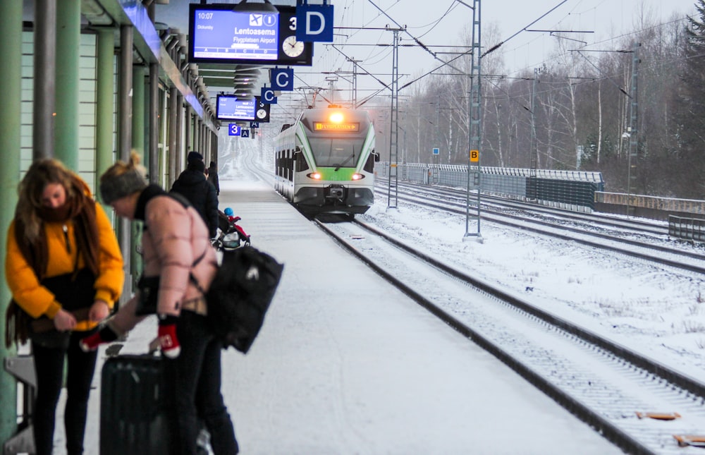 two women holding luggage standing near railway