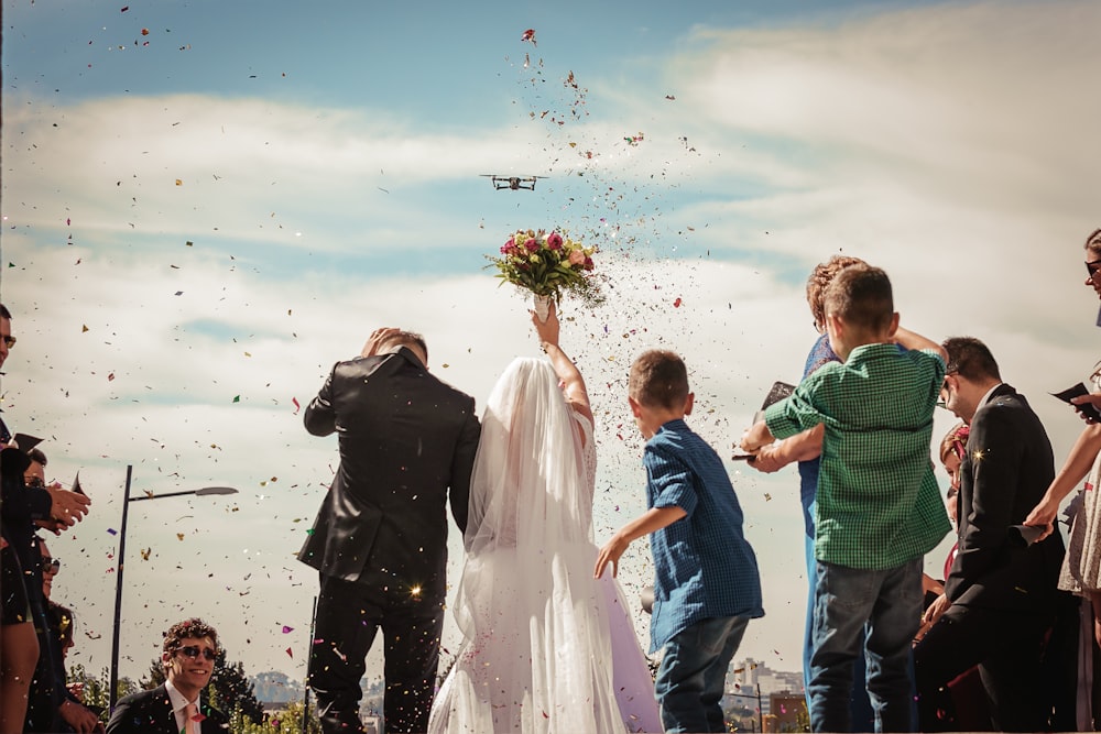 marié debout à côté de la mariée sur le point de jeter le bouquet de fleurs