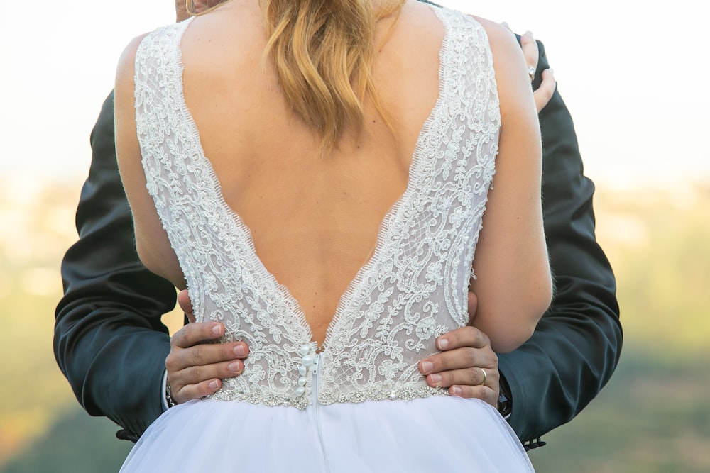 woman in white dress standing in front of man holding her waist