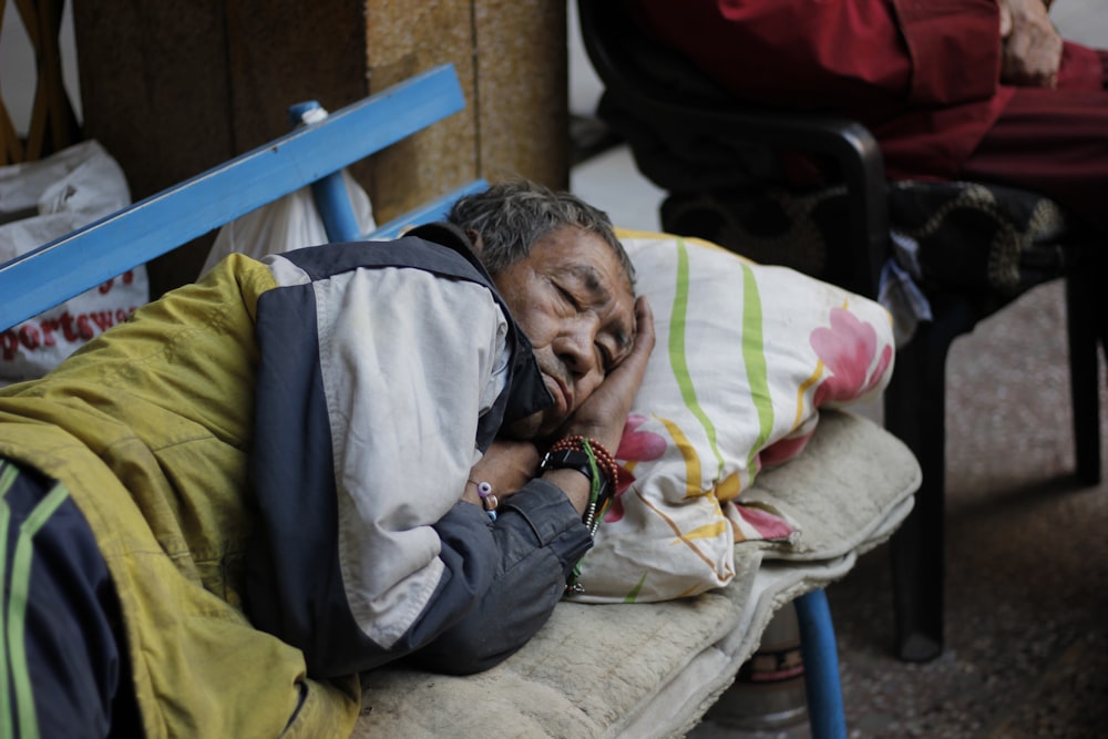 woman sleeping on blue and gray bench