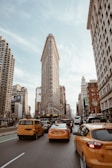 assorted-color vehicle passing near Flat Iron building during daytime
