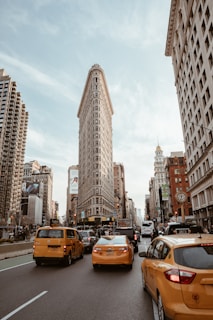 assorted-color vehicle passing near Flat Iron building during daytime