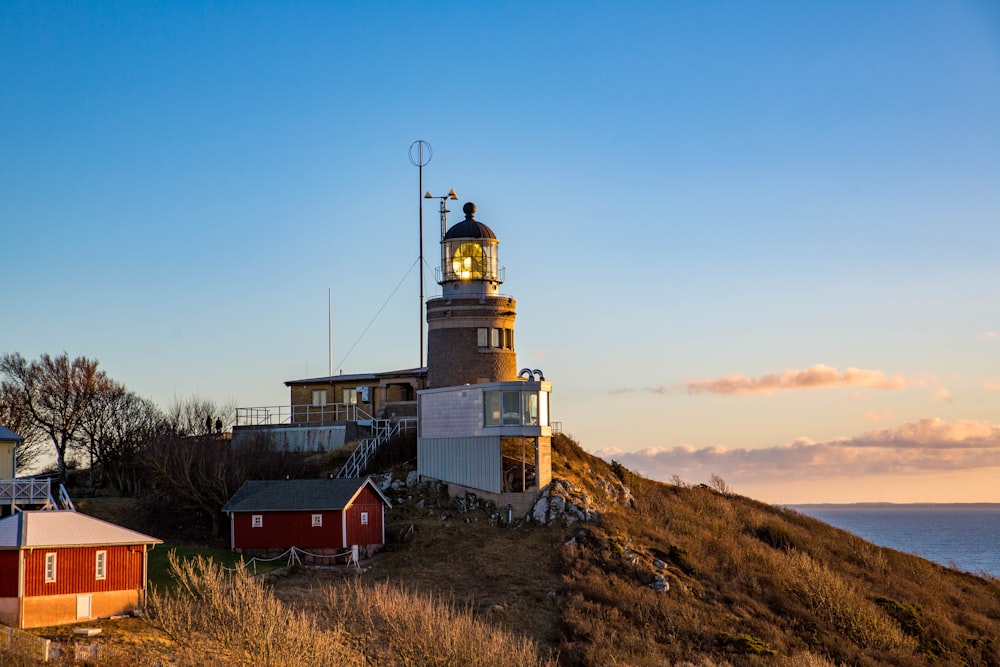 white and brown lighthouse on crest of hill