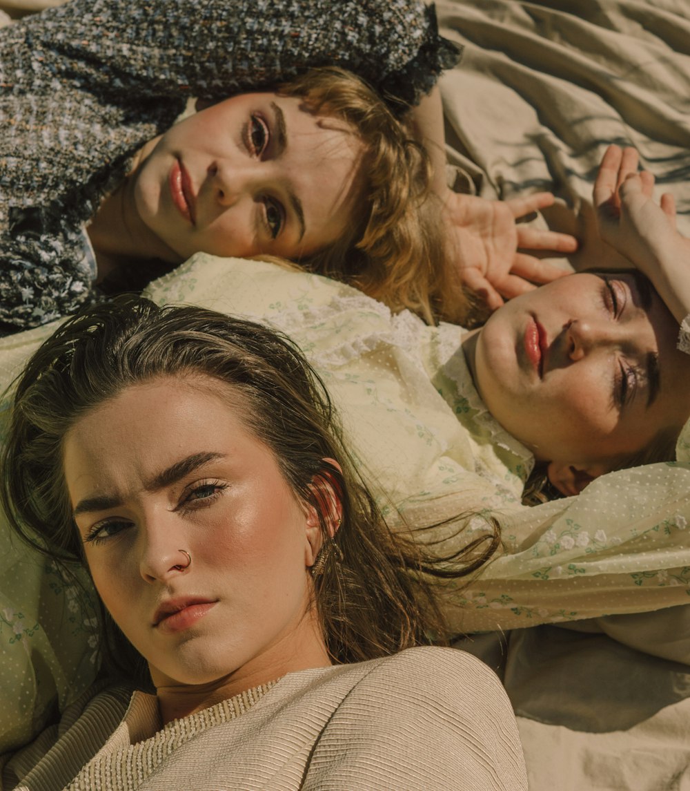 three women lying on white surface