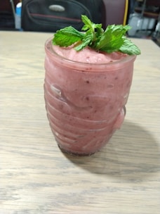 A vibrant glass of creamy papaya milk garnished with fresh mint leaves.