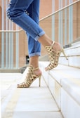 Mujer con sandalias de tacón de cuero marrón caminando por la escalera