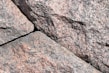 A close-up view of rough, textured granite stones with visible grain and natural color variations. The stones are arranged with visible gaps in between, highlighting their irregular, natural formation.