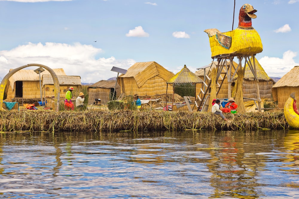 people near brown thatched houses across river