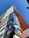 A high-rise building towers upwards with a colorful geometric mural adorning its facade. The mural features abstract shapes in vibrant blues, oranges, and yellows. The sky is clear and blue, providing a striking backdrop to the building's modern design.