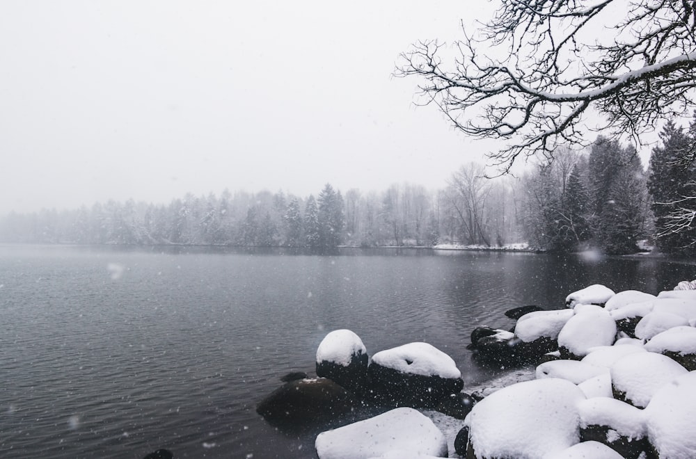 rocks covered with snow near body of water