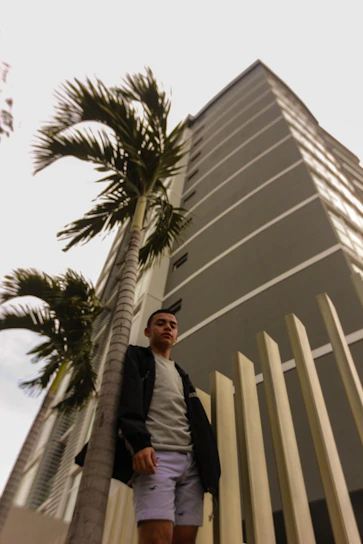 A confident man in terravibe attire standing against a backdrop of towering city skyscrapers at dusk.
