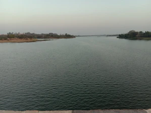 A serene river flowing through untouched natural landscape under a calm sky.