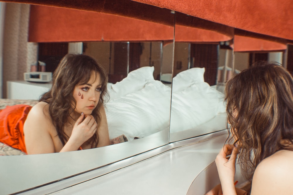 woman lying on bed looking at mirror