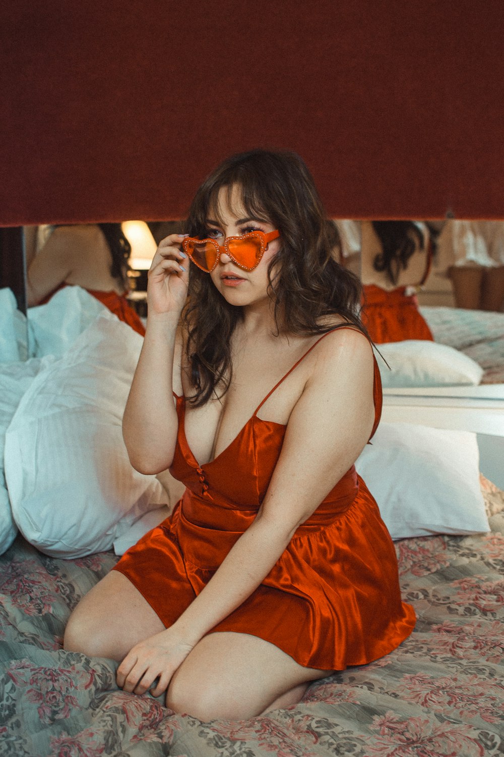 Frau mit orangefarbenem Spaghettiträgerkleid sitzt auf dem Bett