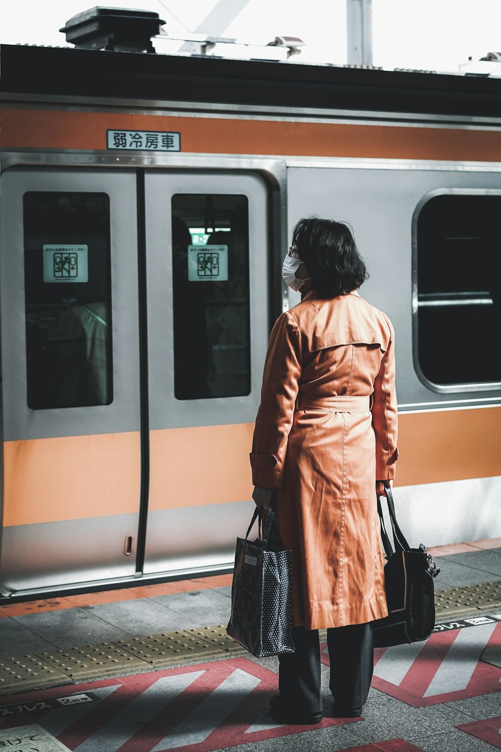 woman wearing brown coat standing in-front of grey train