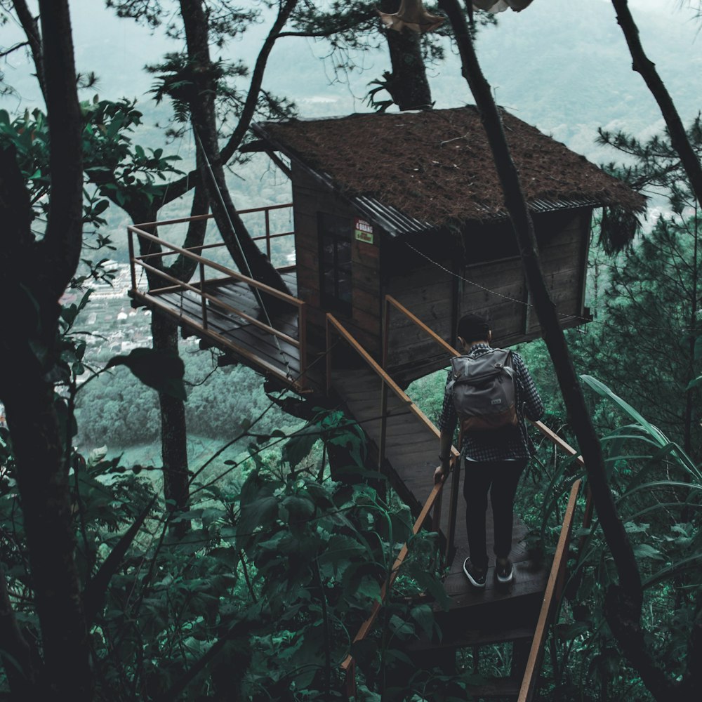 person carrying backpack walking on tree house during daytime