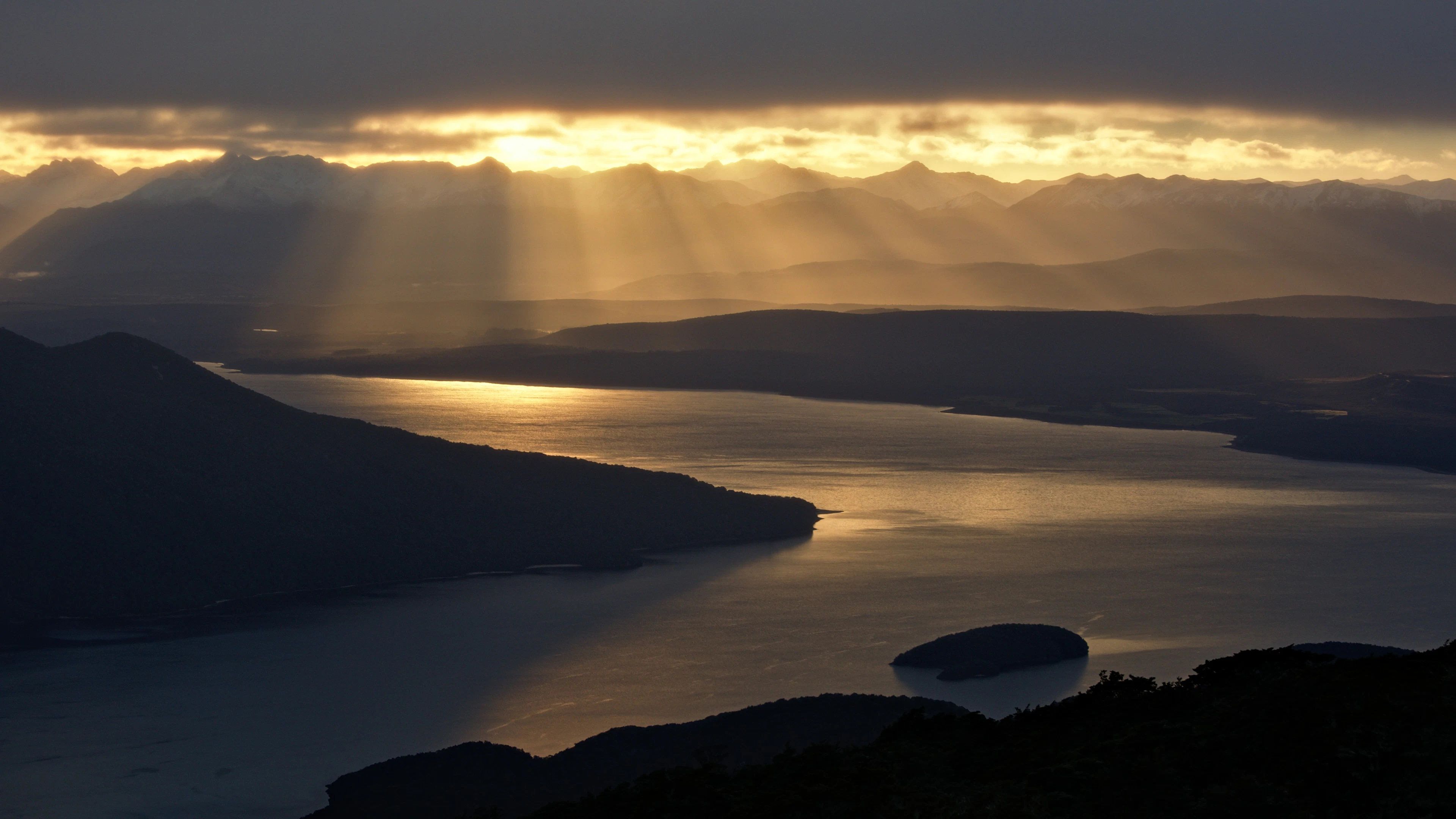 Golden sunrise through the clouds above Lake Te Anau, seen from the Kepler Track