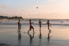 Players diving for the ball on a sandy beach.