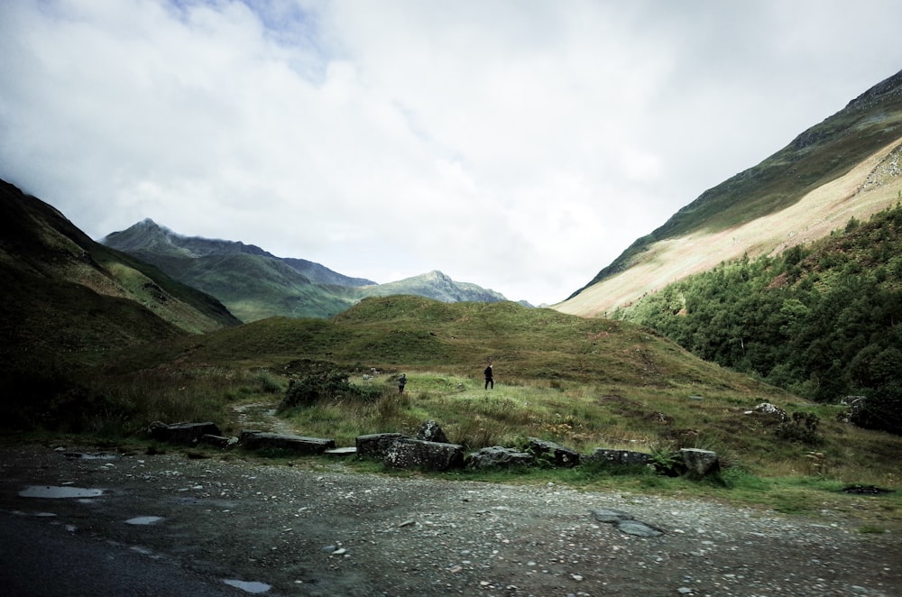 person walking on grass field surrounding mountain scenery