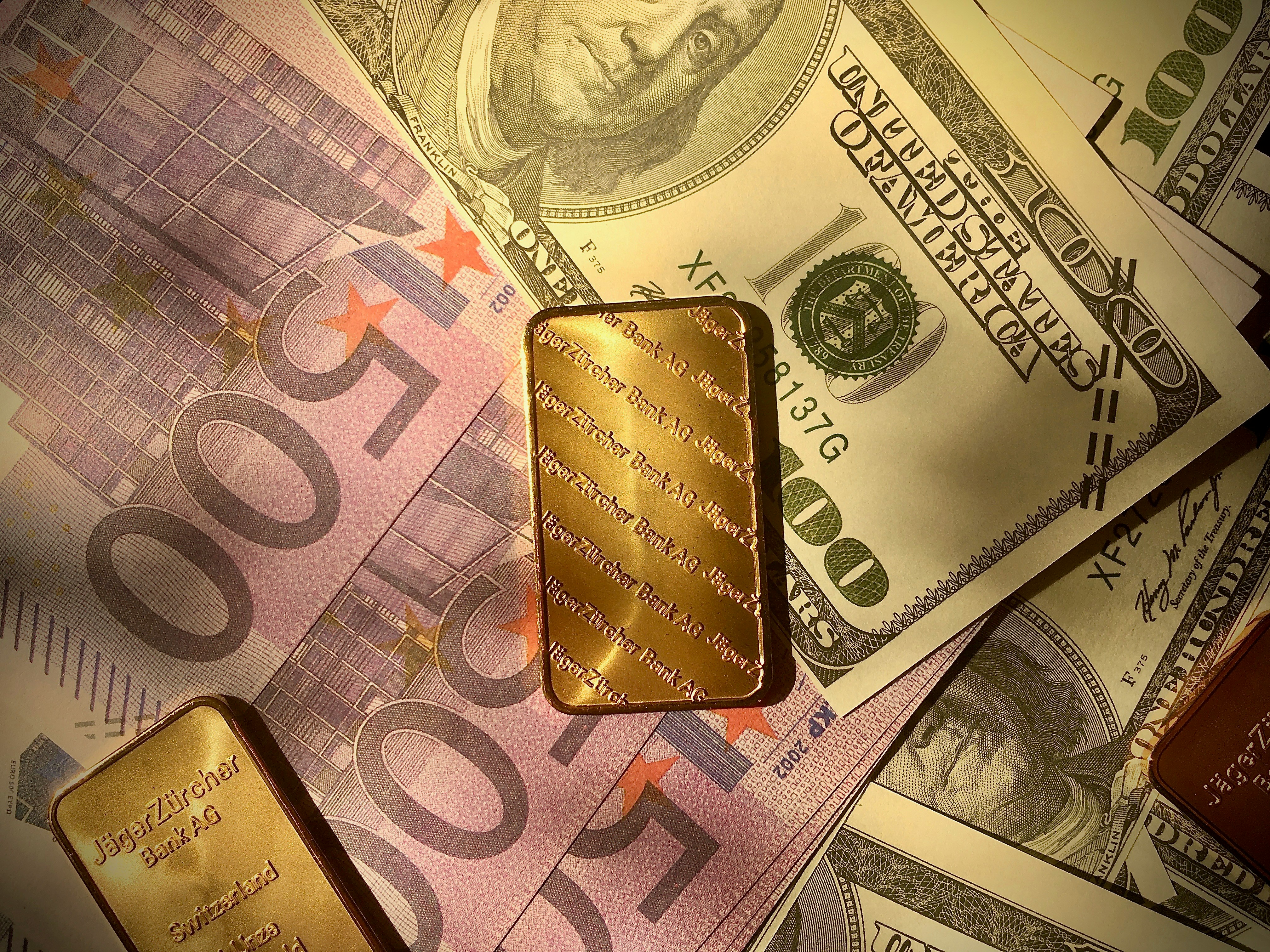 Gold bars and currency exchange symbols on dark background with warm ambient lighting
