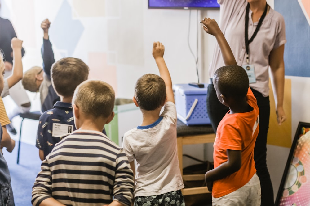 teacher teaching children raising hands in classroom