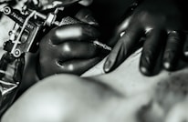 Close-up of a tattoo machine in action with ink droplets and focused lighting highlighting the equipment's quality.