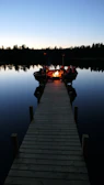 Elegant lakeside fire pit surrounded by warm wood seating and soft lighting.