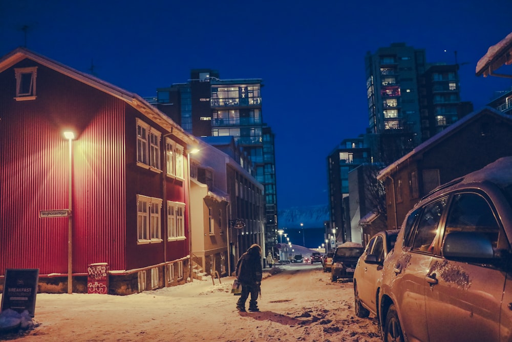 a man standing in the snow next to a red building