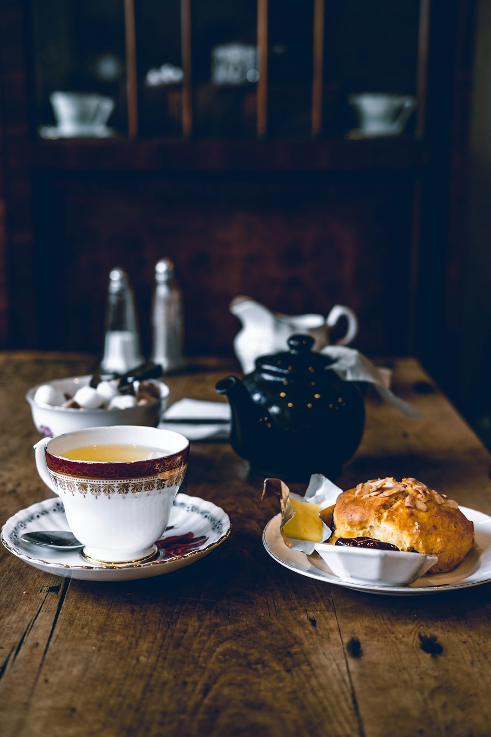 coffee pot beside bread on plate and teapot on table