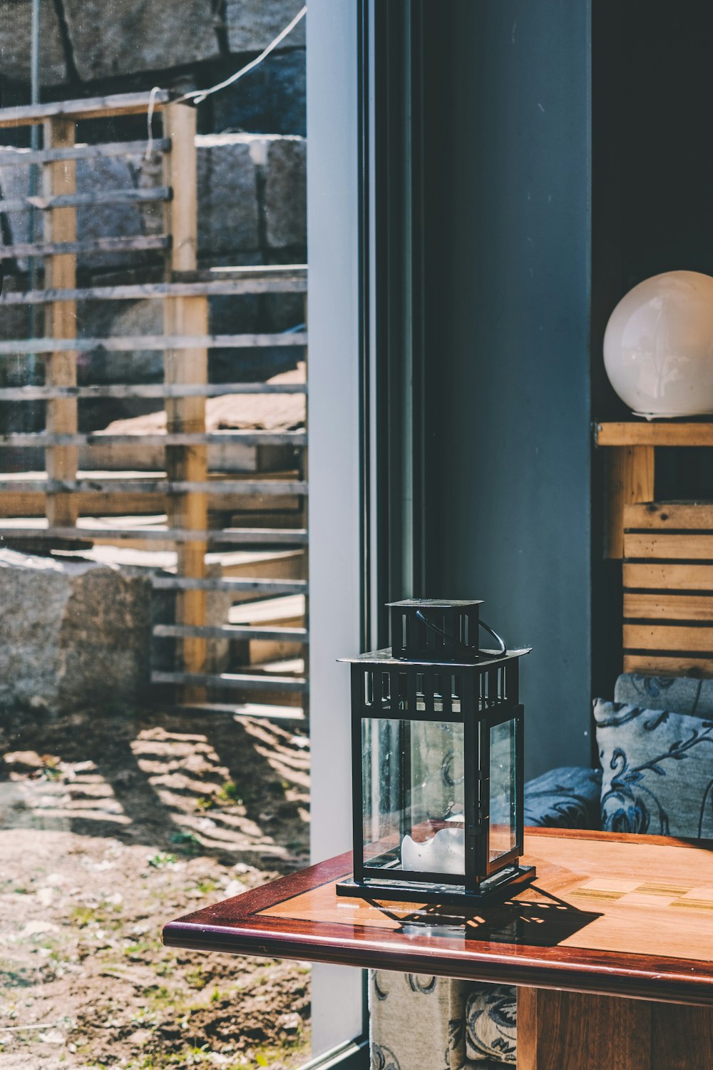 black metal framed candle lantern on top of red wooden table