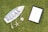 A surfboard-shaped sign with the words 'Relax, Life is Good' printed on it is placed on grass. Attached to the sign are a starfish and a seashell. Nearby is an empty black picture frame with a white space inside.