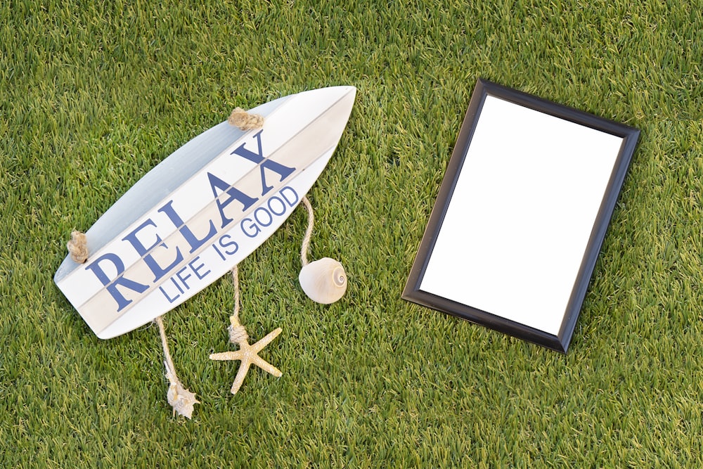 black photo framed and relax board sign on grass