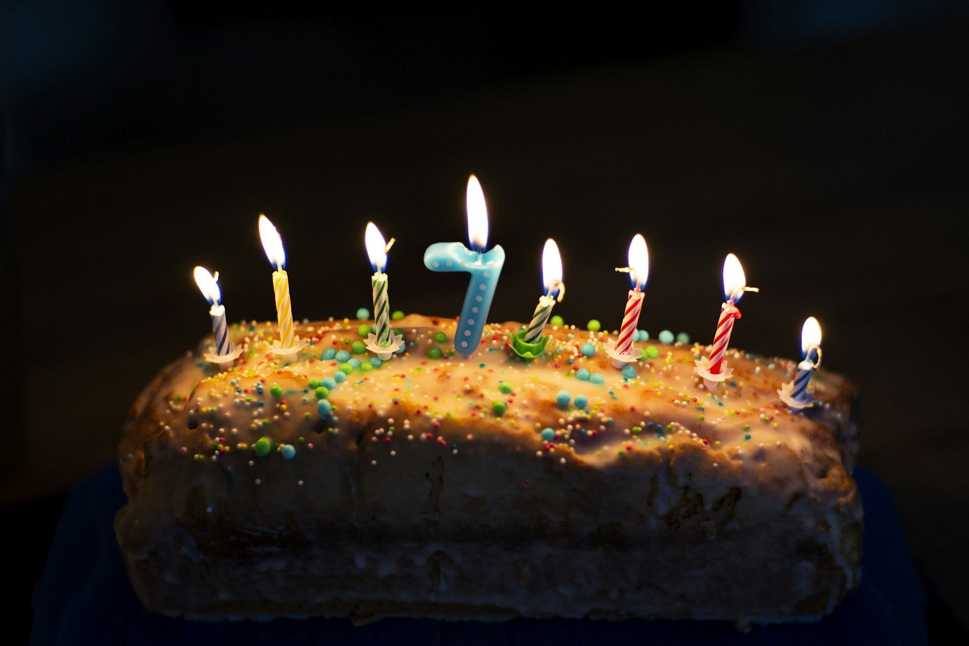 A colorful birthday cake with ten candles, decorated with vibrant frosting and edible glitter.