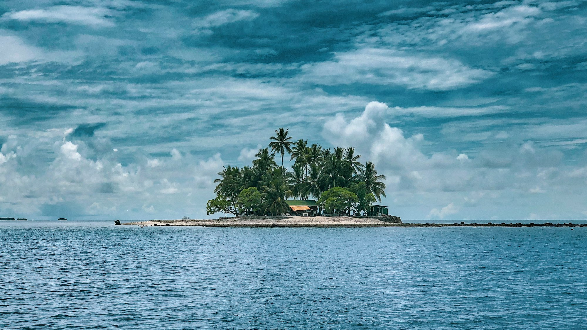 A tropical island under a partly cloudy sky.