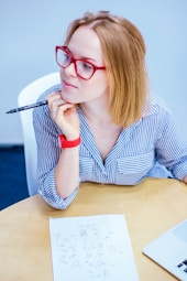 woman holding black pen sitting on white chair