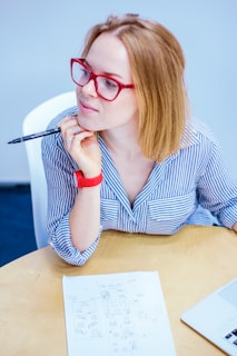 woman holding black pen sitting on white chair