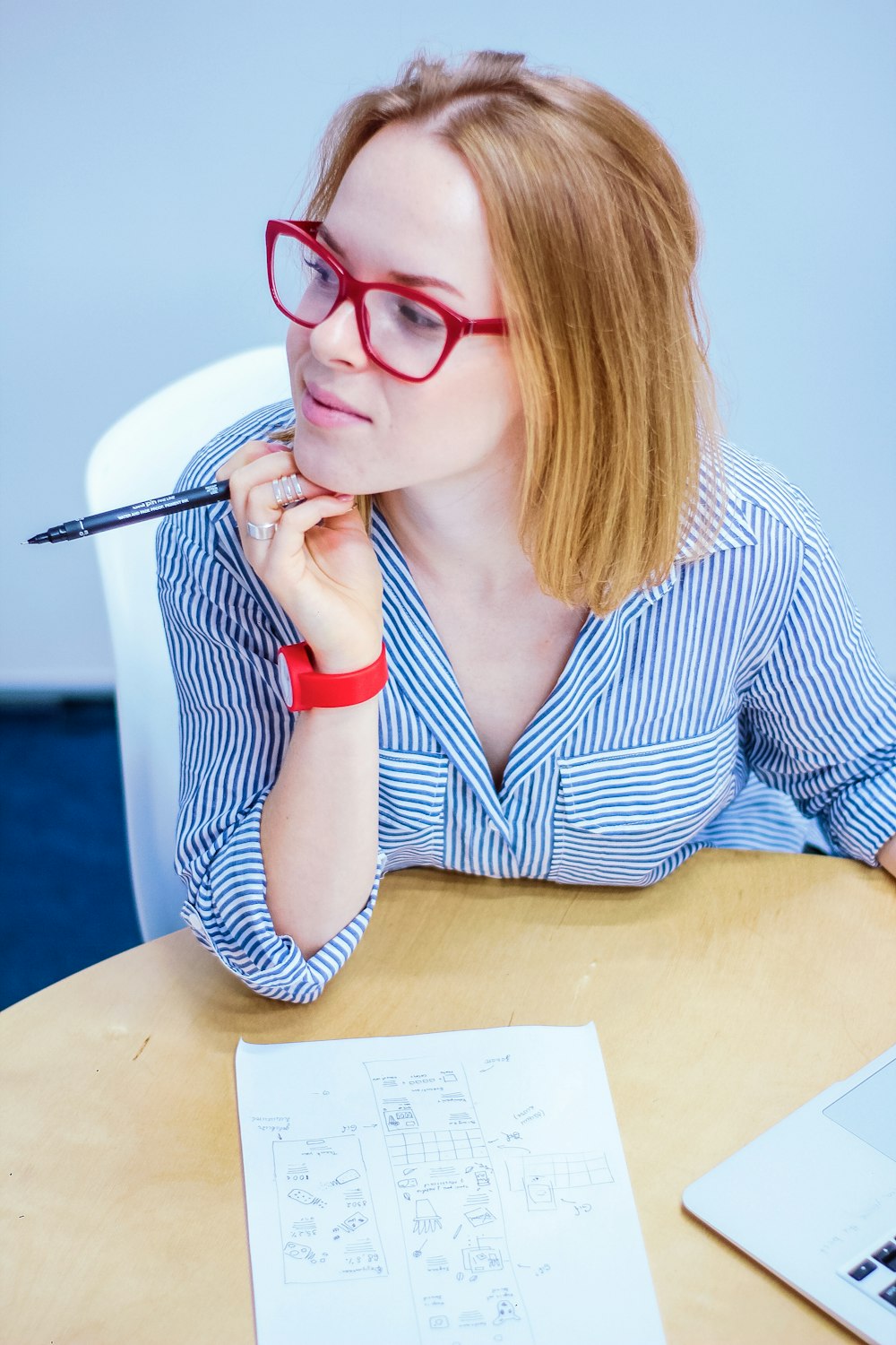 woman holding black pen sitting on white chair
