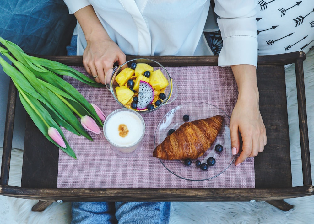 flat-lay photography of croissant on glass plate beside glass of milk