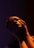 A person is illuminated by dramatic lighting creating a play of shadows and highlights on their face. The hands are gently touching the face, adding an element of contemplation or introspection.