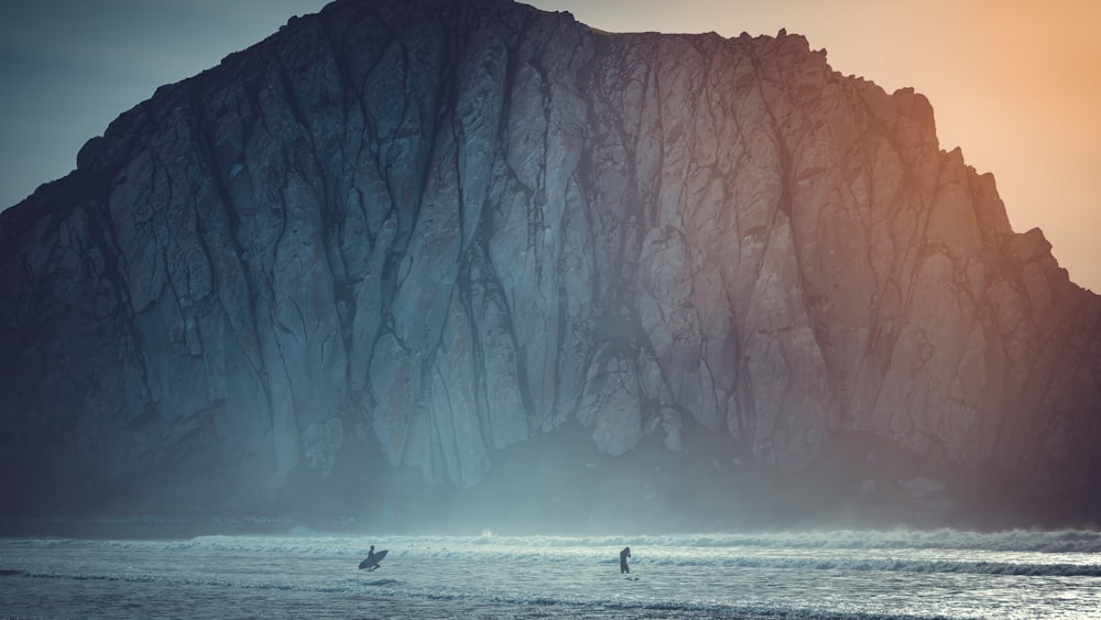 Surfista no corpo de água perto do penhasco durante o dia