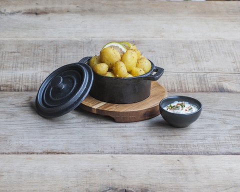 A rustic wooden table with a variety of golden potato dishes including spirals, puffer, and rosemary potatoes, garnished with fresh herbs.