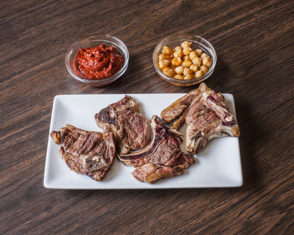 grilled meat on plate beside beans