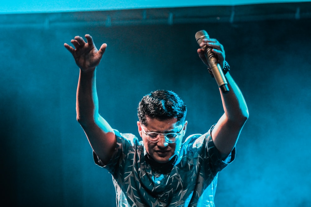 man holding microphone raising hands